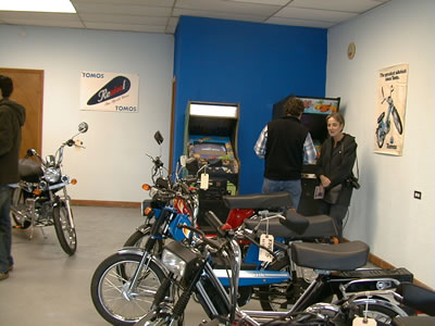 Mopeds on the showroom floor and my parents standing by video games